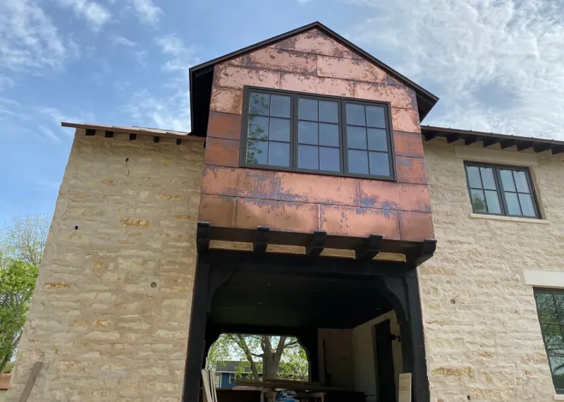 Copper metal panel facade on a stone building for Roof Repair in Waukee